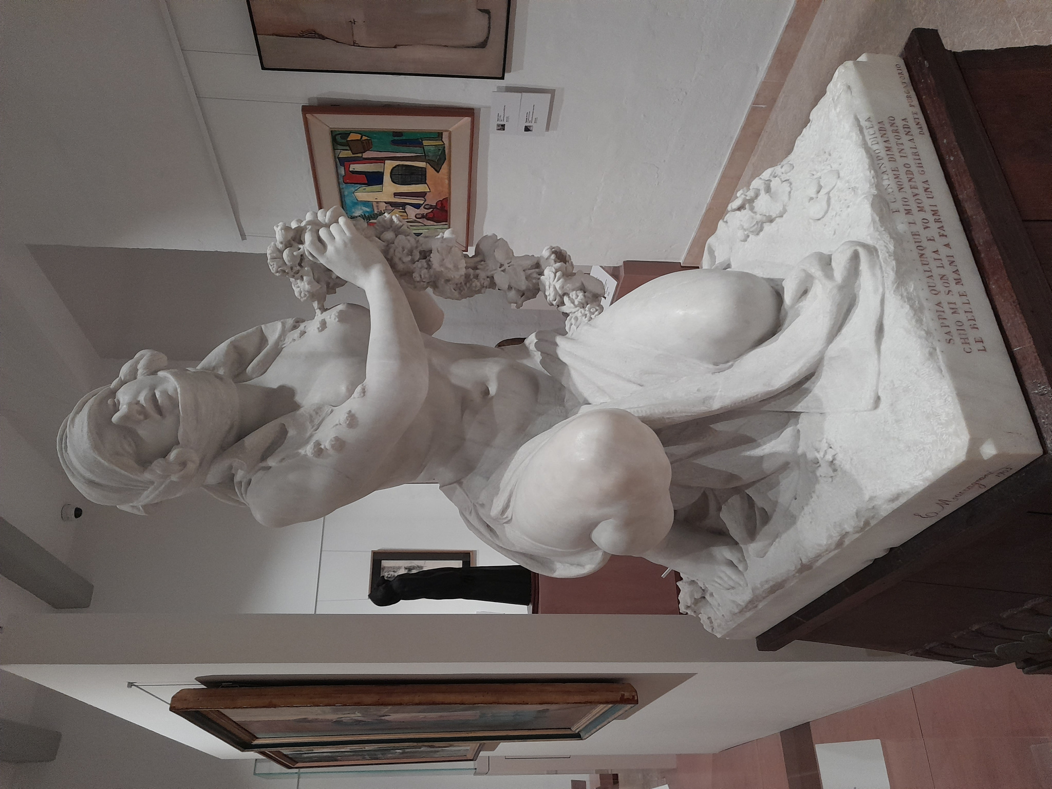 Escultura em mármore de Lia, obra de Eugenio Maccagnani, retratando a personagem bíblica ajoelhada com flores nas mãos.